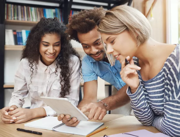 group-three-young-good-looking-startupers-sitting-light-coworking-space-talking-about-future-project-looking-through-design-examples-digital-tablet-friends-smiling-talking-about-work