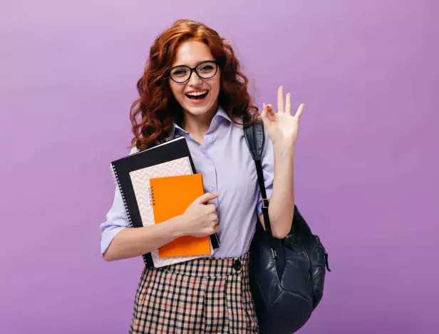 red-haired-lady-eyeglasses-holds-books-shows-ok-sign-compressed